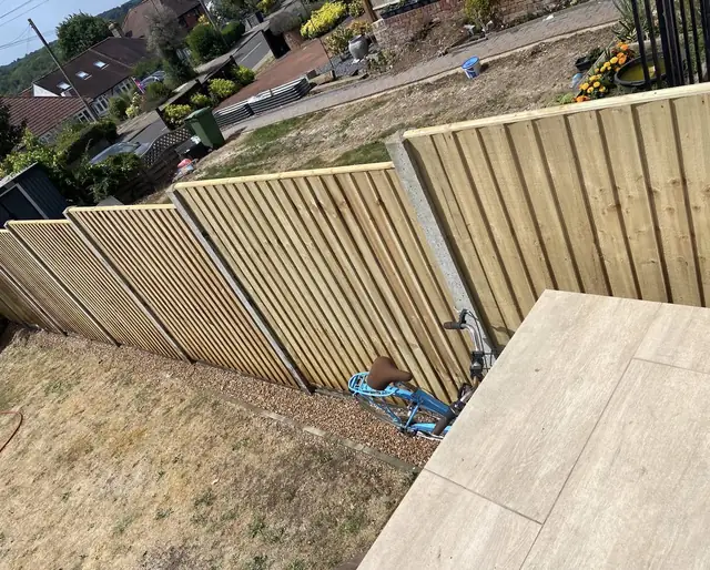 Long run of new closeboard fence panels on concrete posts beside a porcelain patio