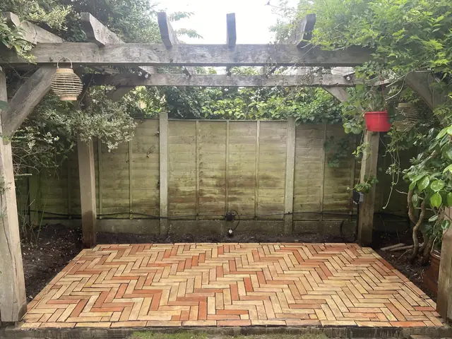 Terracotta-toned paving laid under a timber pergola