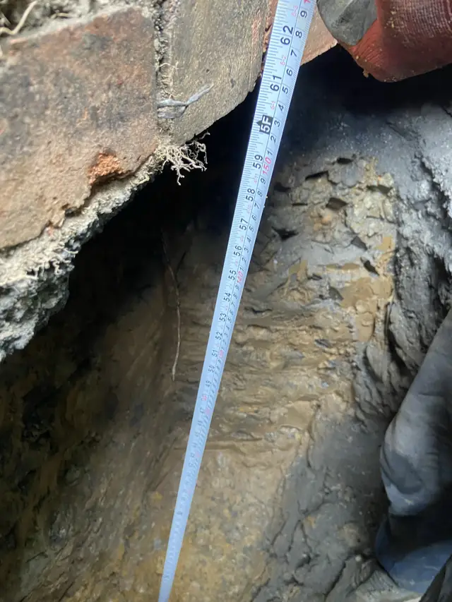 Excavated underpinning section measured against a tape