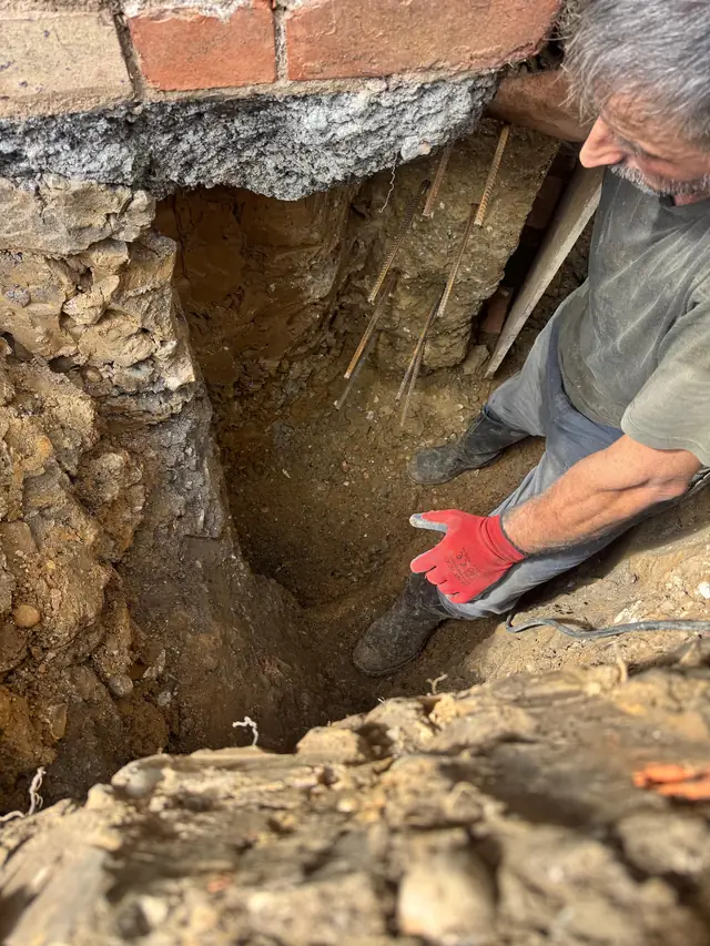 Working in a deep underpinning pit dug beneath a brick wall